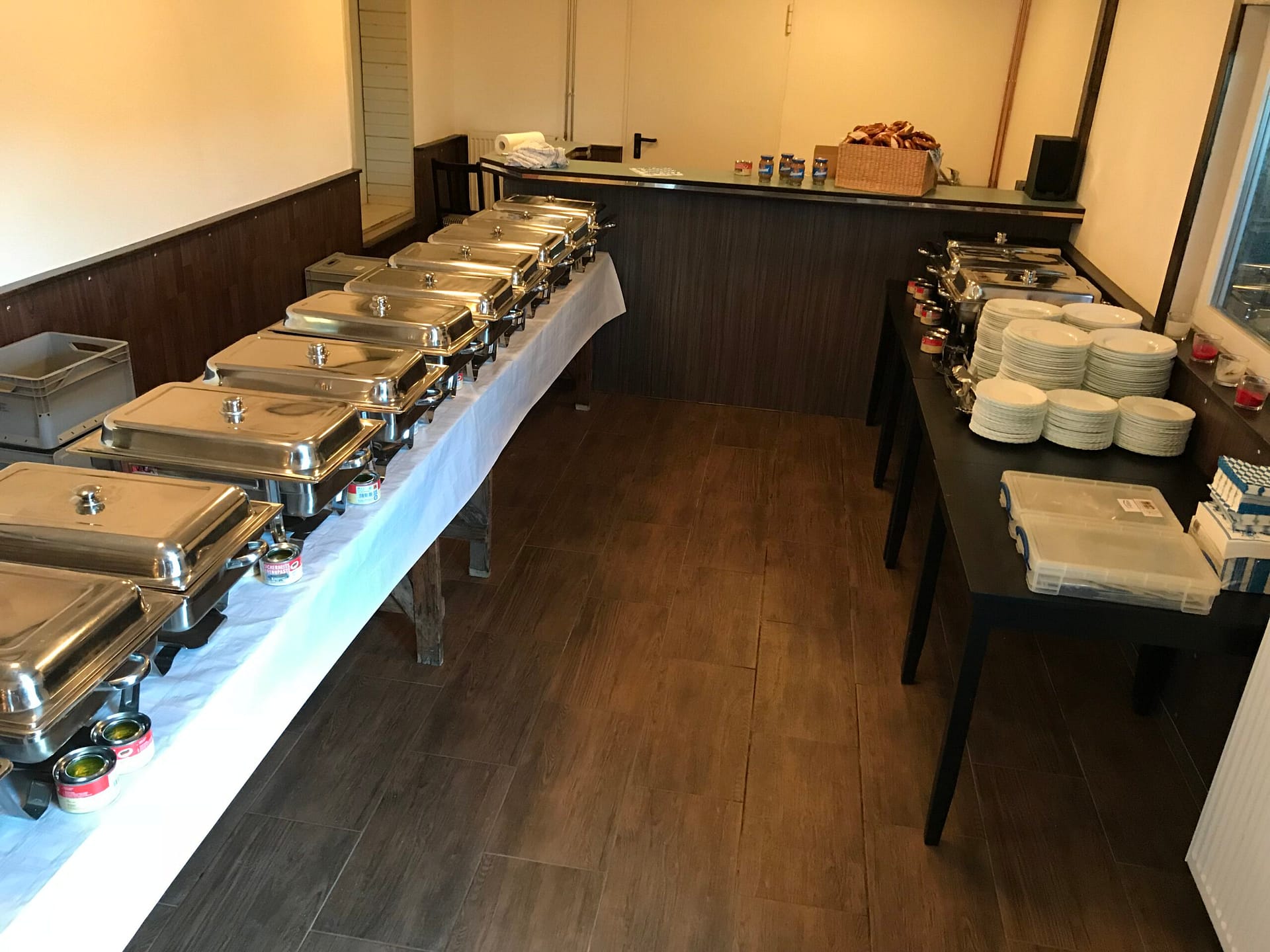 Buffet mit mehreren Warmhaltebehältern auf einem Tisch in einem Innenraum.