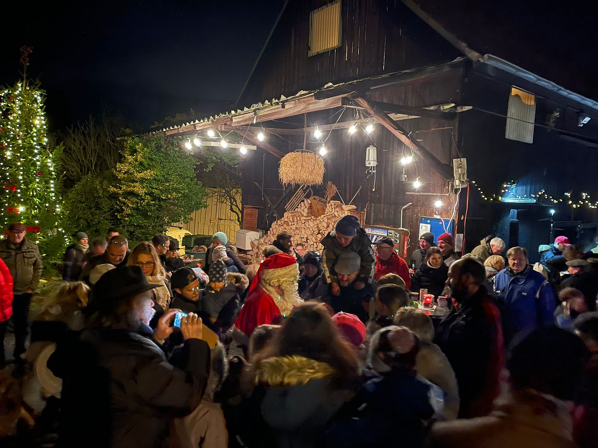Eine Menschenmenge versammelt sich um einen Weihnachtsmann bei einer Veranstaltung im Freien.