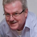 Ein Mann mit grauen Haaren und Brille, der lächelt und in die Kamera schaut.