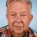 Porträt eines älteren Mannes mit grauen Haaren und kariertem Hemd auf blauem Hintergrund.