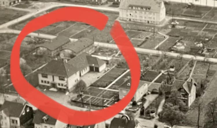 Luftaufnahme eines Wohngebiets mit mehreren Gebäuden und Gärten in der Umgebung.